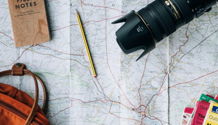 flat lay photography of camera, book, and bag