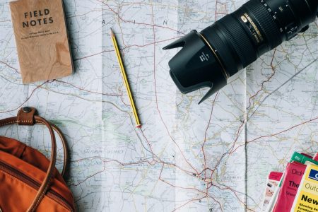 flat lay photography of camera, book, and bag